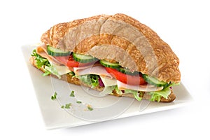 Croissant sandwich with cheese, ham and vegetables. Isolated