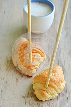 Croissant stab chopstick walk to hot latte coffee cup