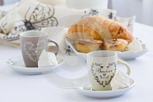 Croissant and a two cups of delicious coffee on a white table