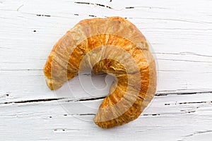 Croissant on white wooden board, view from above.