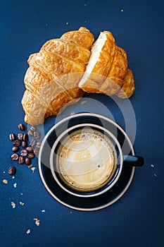 Croissants andcoffee on blue dark tone background. continental breakfast. topview