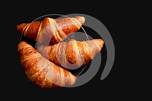 Croissants on a black background with copy space. French cuisine concept. Top view