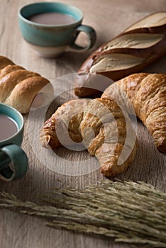 Croissants with bread and coffee cup on wooden background