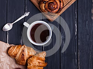 Croissants and coffee in the black wooden table