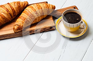 Croissants and coffee on a light background. The concept of delicious breakfast or lunch. At the bottom there is a place for copy