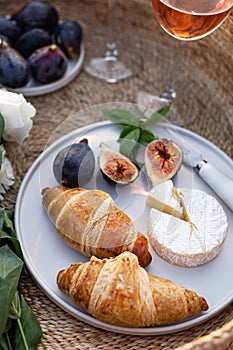 Croissants, figs and camamber cheese in a white ceramic plate