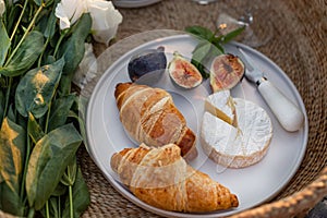 Croissants, figs and camamber cheese in a white ceramic plate