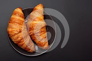 Croissants in a plate on a black background. View from above. French pastries