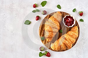 Croissants with strawberry jam on wooden board. Top view with copy space