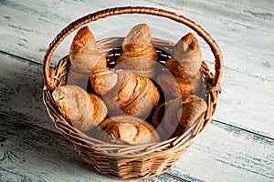 Croissants in a wicker basket on a wooden background