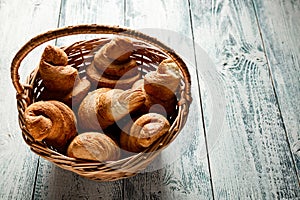 Croissants in a wicker basket on a wooden background with a copy of the space