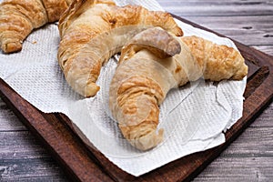 Croissants on a wooden board on a table. Differential focus photo