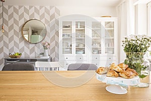 Croissants on wooden dining table in white apartment interior wi