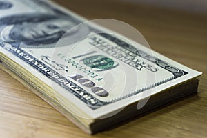 Crolled stack of 100 new dollar bills on wooden background