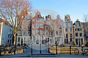 Crooked and colorful heritage buildings, with the bridge Mekmeisjesbrug in the foreground and located along Brouwersgracht Canal,