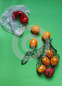 Crooked red pepper in a plastic bag and yellow tomatoes in a string bag, a call to use eco shopping bags