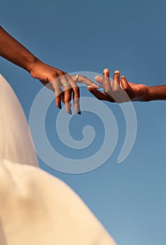 Crop black couple touching fingers against blue sky