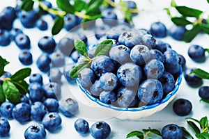 Crop of blueberry or great bilberry in bowl on blue wooden table. Organic superfood and healthy nutrition.