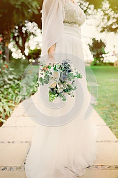 Crop bride with bouquet in park