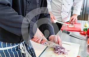 Crop of chefs cutting onions and other food ingredients