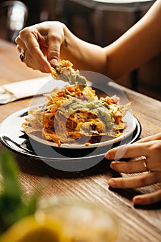 Crop client eating yummy nachos in restaurant