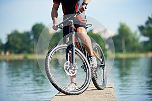 Crop of cyclist posing next to his bike