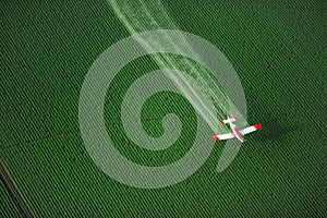 An overhead view of a crop duster spraying green farmland photo