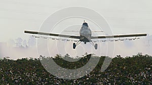 Crop duster spraying chemicals over a cotton field - slow motion