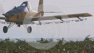 Crop duster spraying chemicals over a cotton field - slow motion