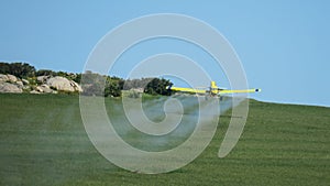 Crop duster spraying fertliizer over green crops