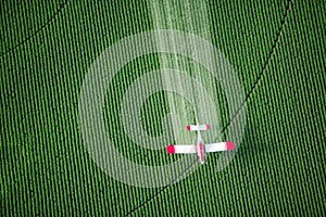 A crop duster spraying a green farm field.