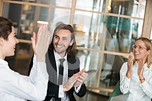 Excited business partners applauding congratulating colleague wi photo