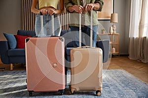 Crop of family couple going for trip posing with packed luggage suitcases at home