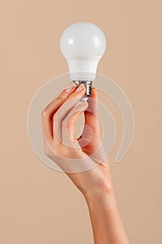 Crop hand demonstrating LED light bulb in studio