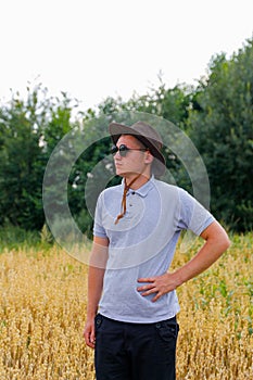 Crop and harvest. Portrait of farmer standing in gold wheat field with blue sky in background. Young man wearing