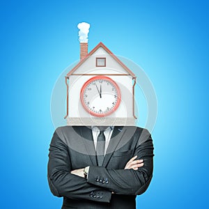 Crop image of a businessman with arms folded and a house with a smoking chimney and a clock-face on front wall instead