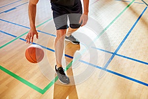 Crop man dribbling basketball ball