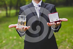 Crop of man wearing a suit and tie holds the perfume and cufflinks - groom wedding accessories