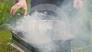 Crop person warming up frying pan on brazier in garden