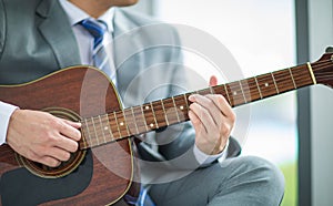 Crop photo businessman wearing suit relaxing by playing guitar feel casual and relaxation in work office