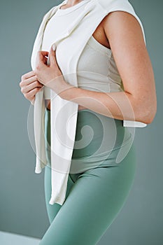 Crop photo of young woman in sportswear on background of grey wall