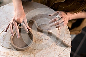 Crop potter making coil vessel on marble table in workshop
