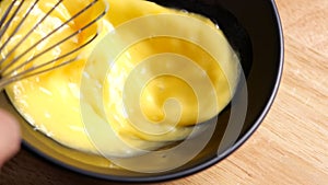 Crop shot of preparing homemade omelette mixing with whisk eggs in slow motion