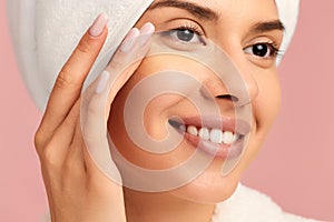 Crop smiling woman applying concealer under eyes