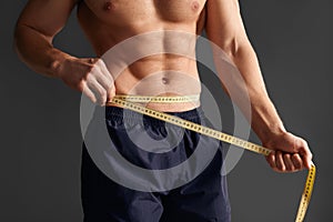 Crop sportsman measuring waist