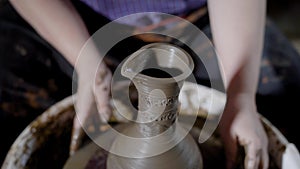 Crop talented hands of artisan creating earthenware on potter`s wheel in craft studio