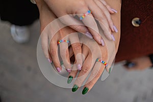 Crop of three girls showing her stylish manicure, holding their fingers on black leather handbag. Different design of