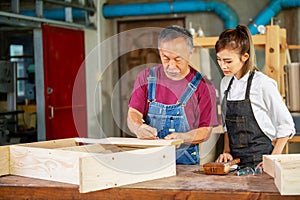 Crop unrecognizable craftswoman making marks on wooden detail while working with anonymous colleague in carpentry workshop