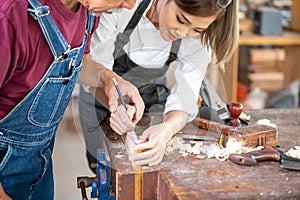 Crop unrecognizable craftswoman making marks on wooden detail while working with anonymous colleague in carpentry workshop