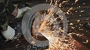 Crop unrecognizable worker cutting metal with angle grinder on construction site